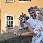 Zwei Personen stoßen mit Bierflaschen an vor der Rathausschänke.