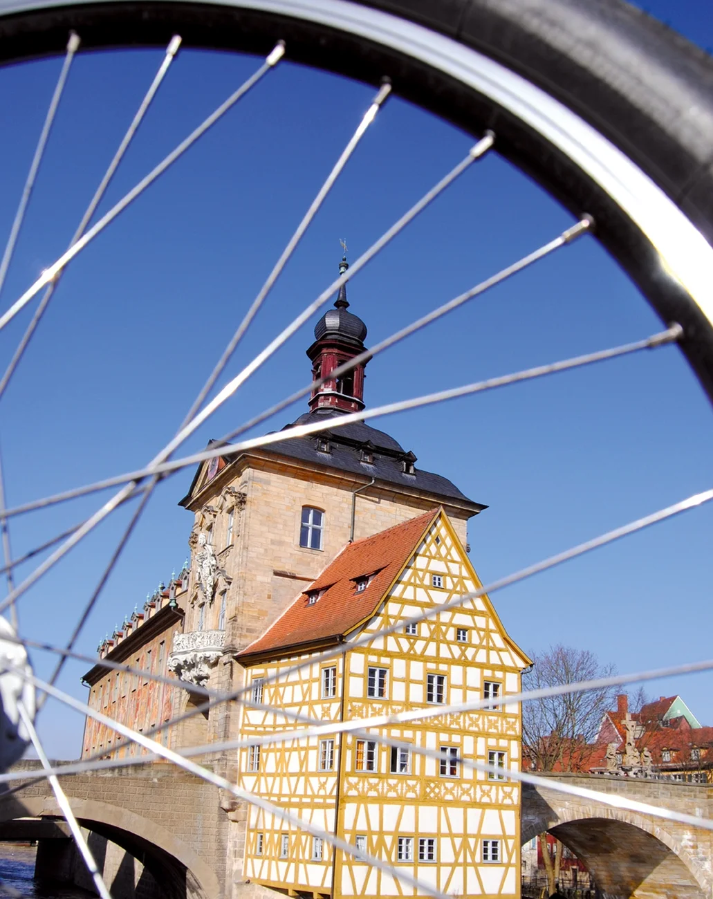 Ein Bild des Alten Rathauses von der Seite durch Fahrradspeichen hindurch.