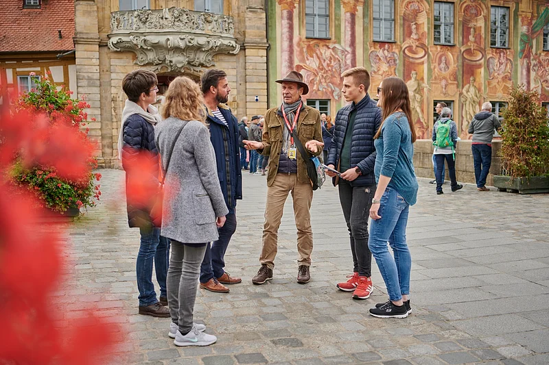 Eine Stadtführungs-Gruppe steht vor dem Alten Rathaus in Bamberg.